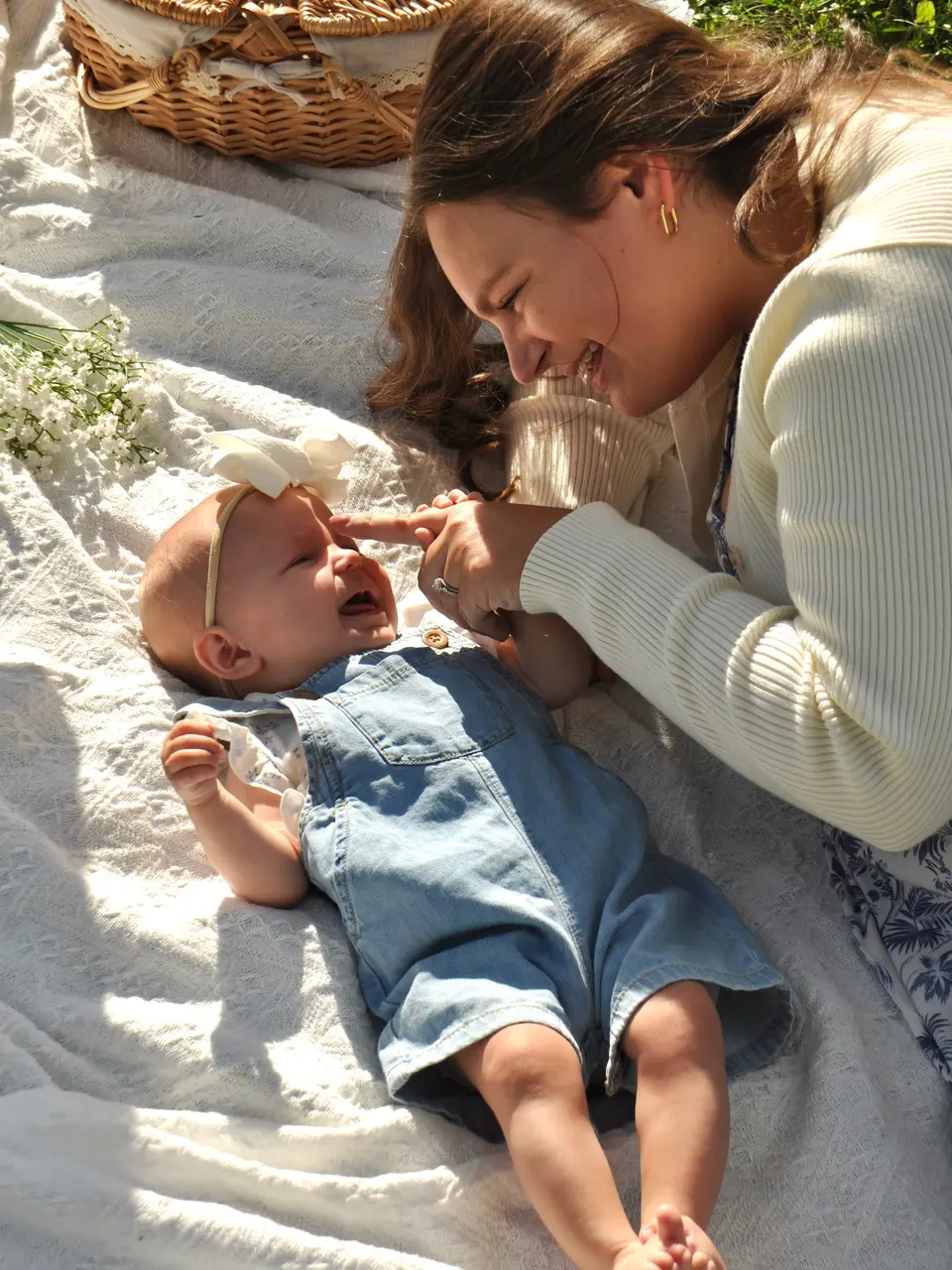 A mother laughing with her baby during a sunlit outdoor family session