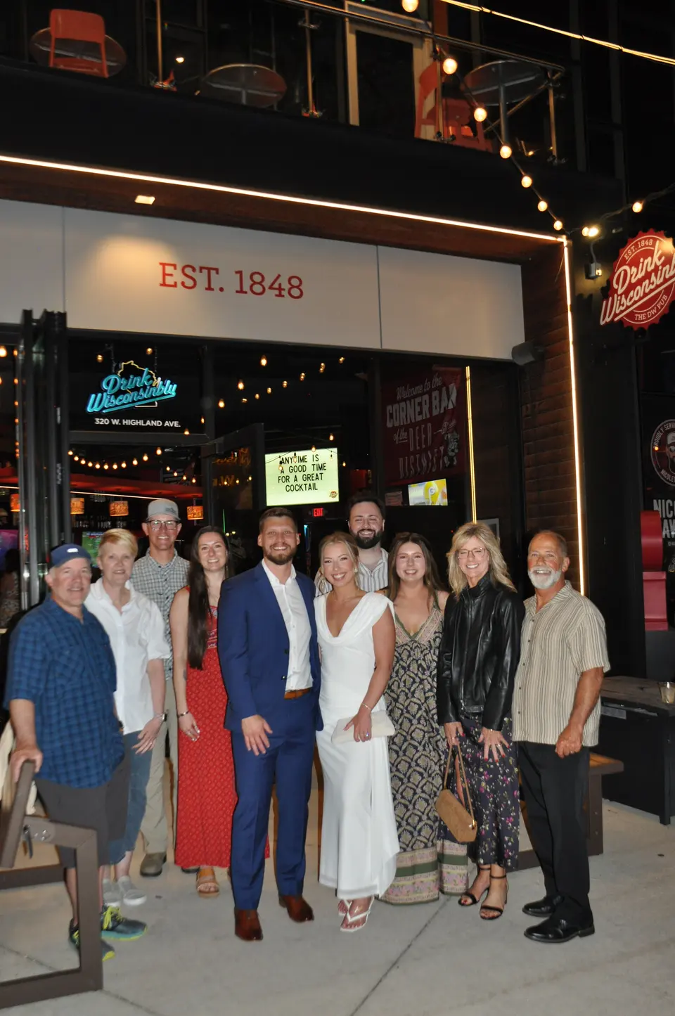 Newlyweds posing with family outside a Milwaukee bar after their wedding