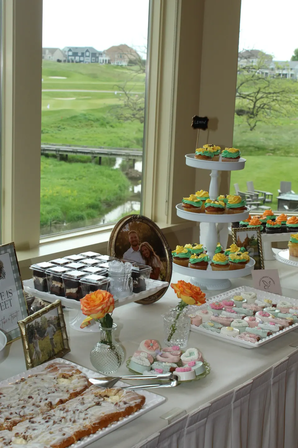 A bridal shower dessert table with floral cupcakes, pastries and roses